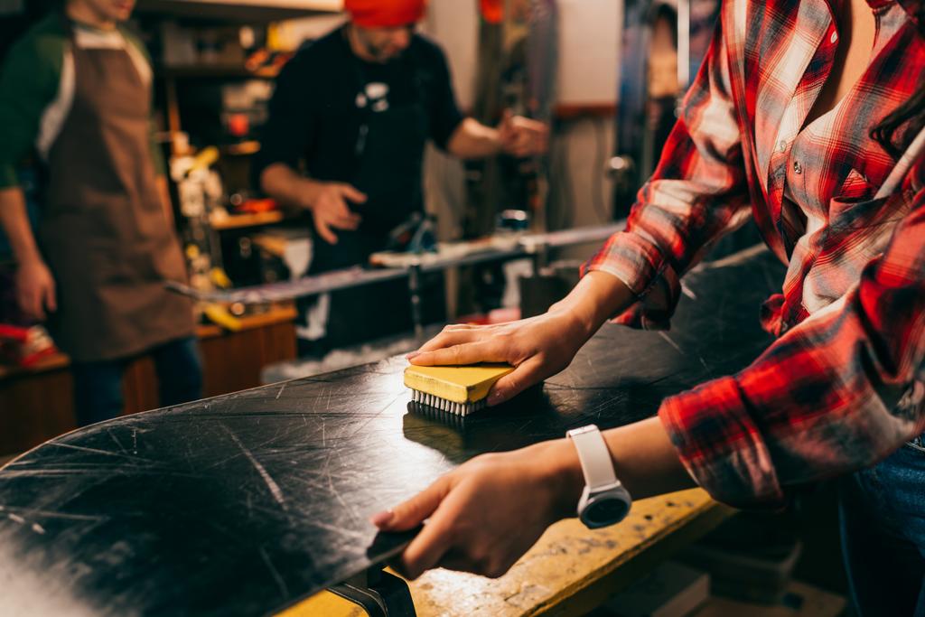 обрізаний вид працівника полірування сноуборду пензлем у ремонтному магазині
  - Фото, зображення