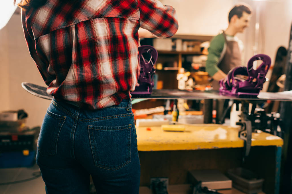 обрезанный вид работника, ремонтирующего сноуборд в ремонтной мастерской
  - Фото, изображение