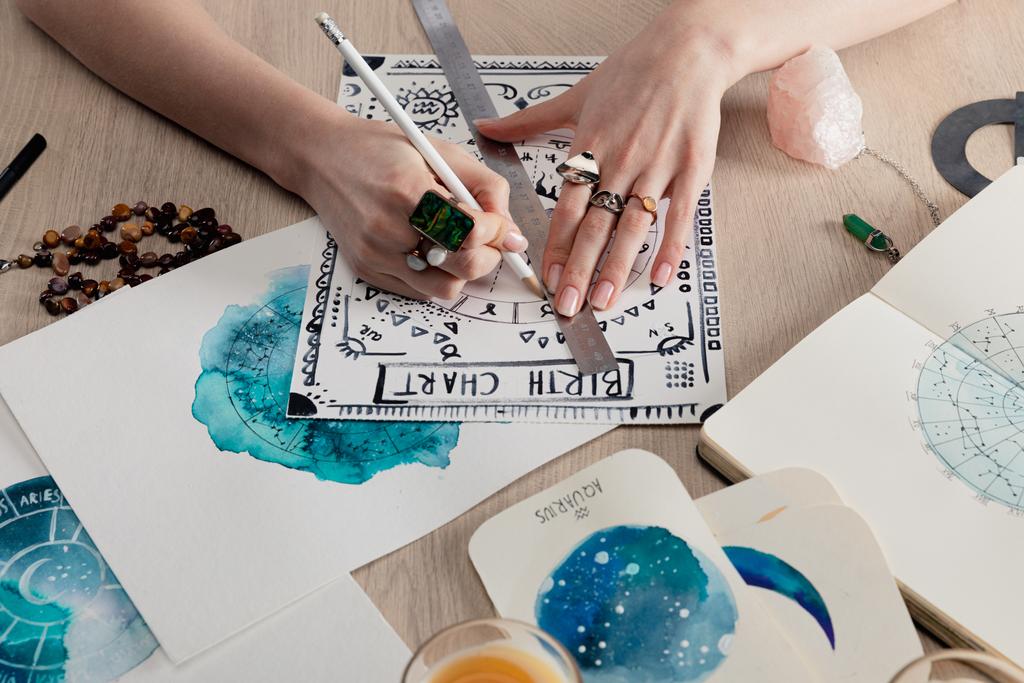 Vista recortada de astrólogo dibujo carta natal por acuarela pinturas con signos del zodíaco en las tarjetas en la mesa
 - Foto, imagen