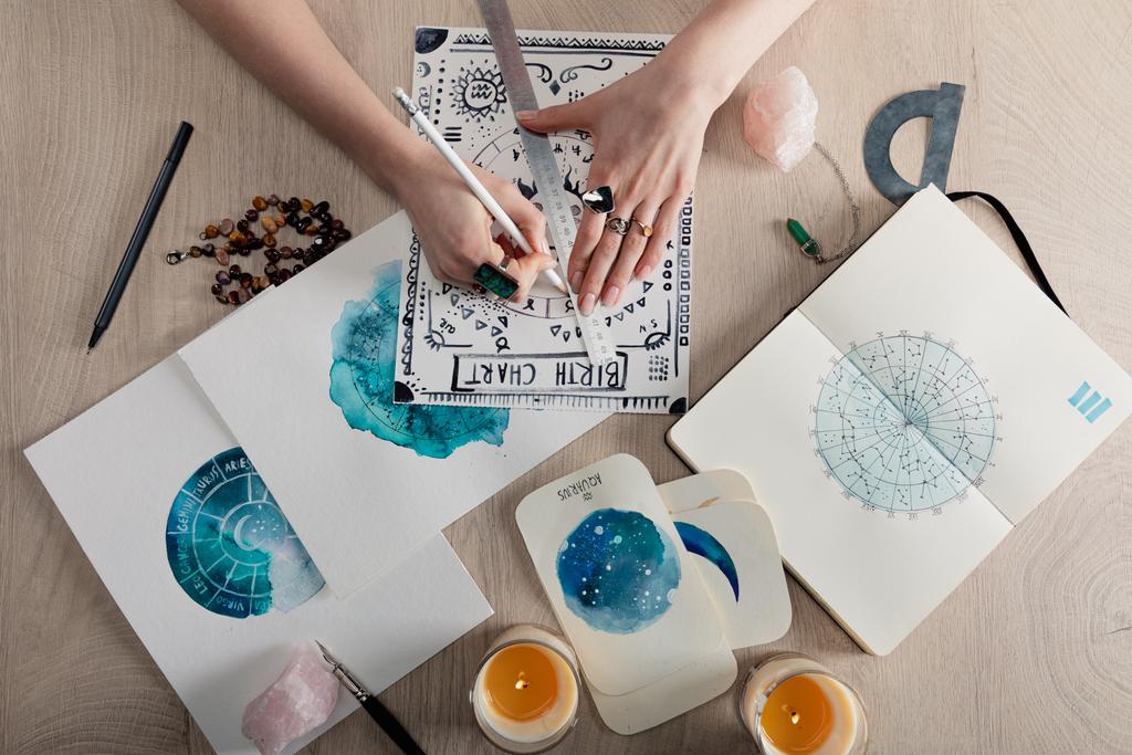 Astrologun doğum çizelgesini mumlarla, kristallerle ve masada suluboya resimlerle çizmesinin en üst görüntüsü  - Fotoğraf, Görsel