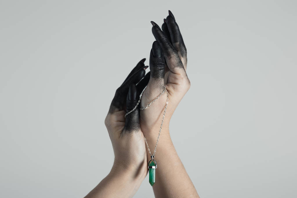 Καλλιεργημένη άποψη των χεριών μάγισσα σε μαύρο λόγω κρατώντας κρύσταλλο απομονώνονται σε γκρι  - Φωτογραφία, εικόνα
