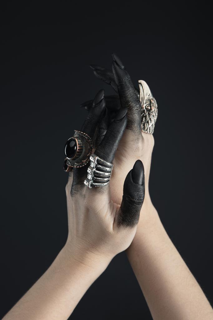 Oříznutý pohled na ruce čarodějnice s šperky kroužky a černým barvivem izolovaným na černé  - Fotografie, Obrázek