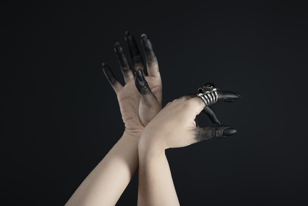 Καλλιεργημένη άποψη των μαύρων βαμμένα δάχτυλα των χεριών μάγισσα με δαχτυλίδια κοσμήματα που απομονώνονται σε μαύρο  - Φωτογραφία, εικόνα