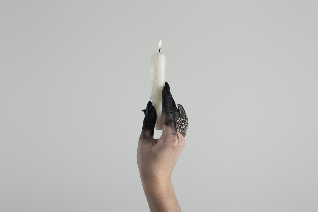 Vista ritagliata della mano strega con anello di gioielli e vernice nera che tiene la candela isolata sul grigio con spazio copia
 - Foto, immagini