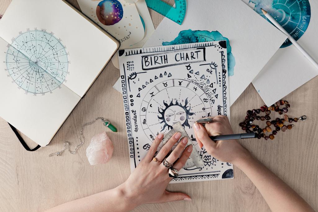 Astrologe malt Geburtshoroskop nach Kristallen und Aquarellzeichnungen auf Karten auf dem Tisch - Foto, Bild