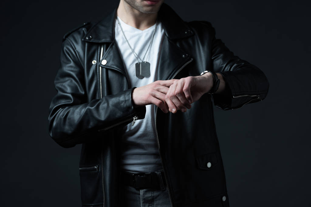 обрезанный вид стильного жестокого человека в байкерской куртке с наручными часами, изолированными на черном
 - Фото, изображение