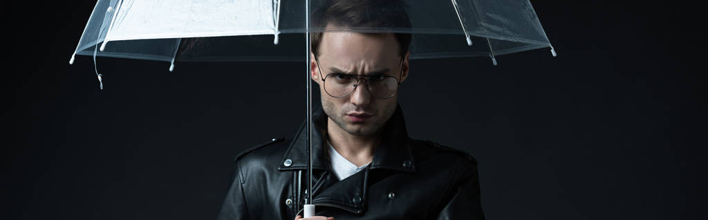 enojado hombre brutal con estilo en chaqueta de motociclista con paraguas aislado en negro, tiro panorámico
 - Foto, imagen