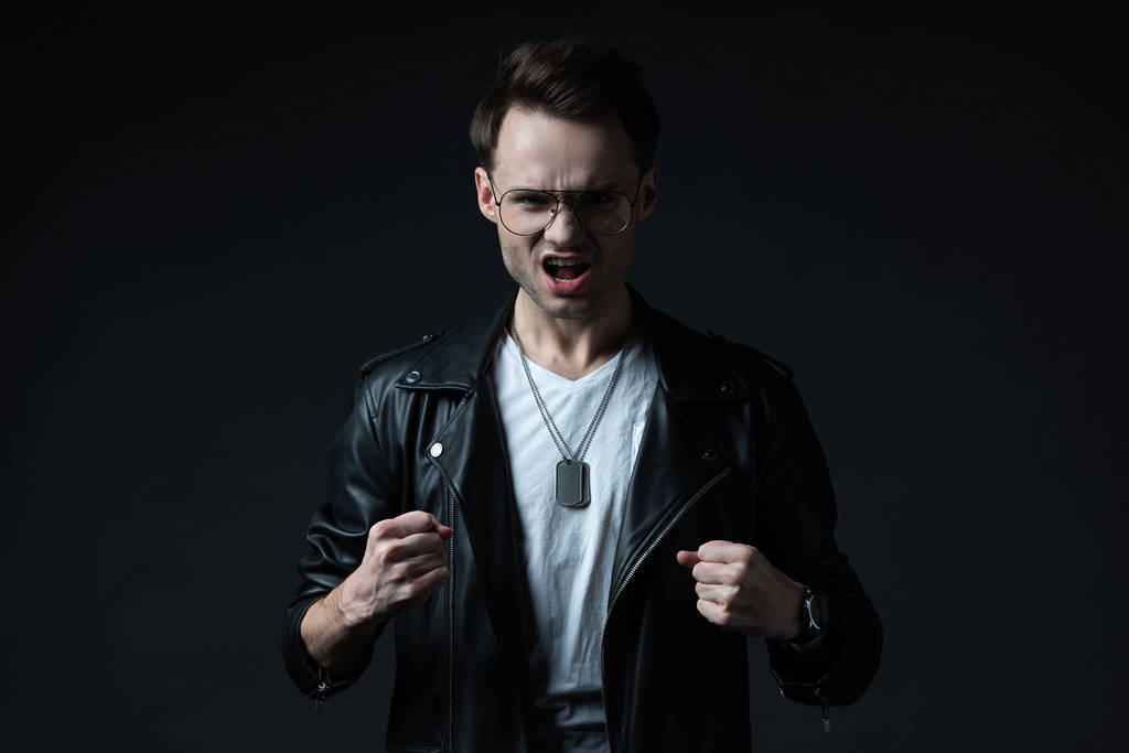 angry stylish brutal man in biker jacket showing fists isolated on black - Photo, Image