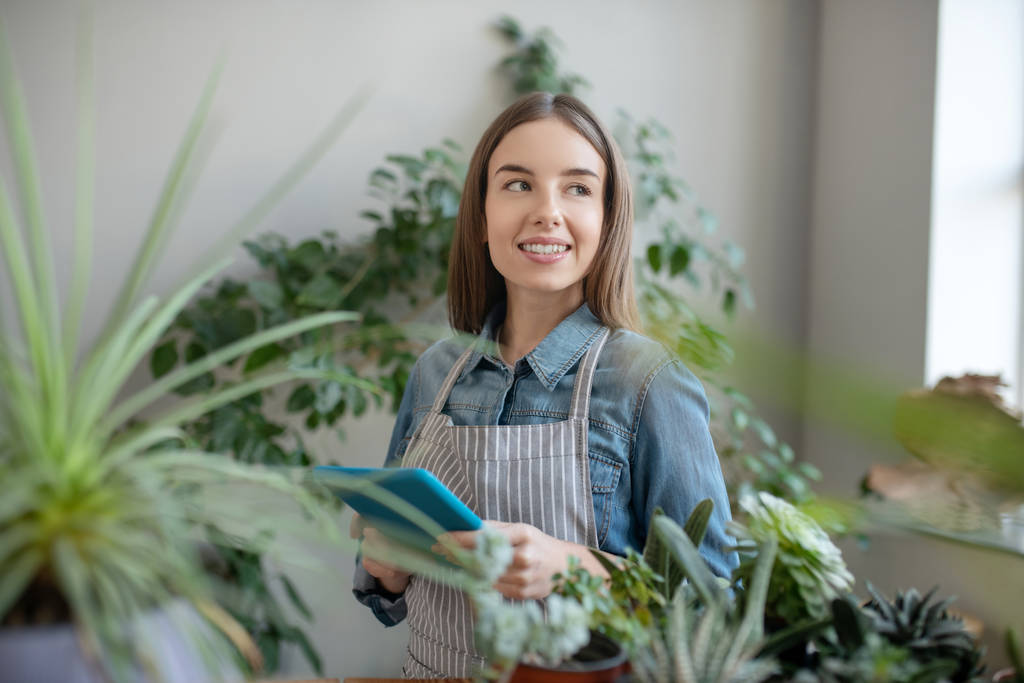 Femme souriante utilisant une tablette dans une maison de plantes
 - Photo, image