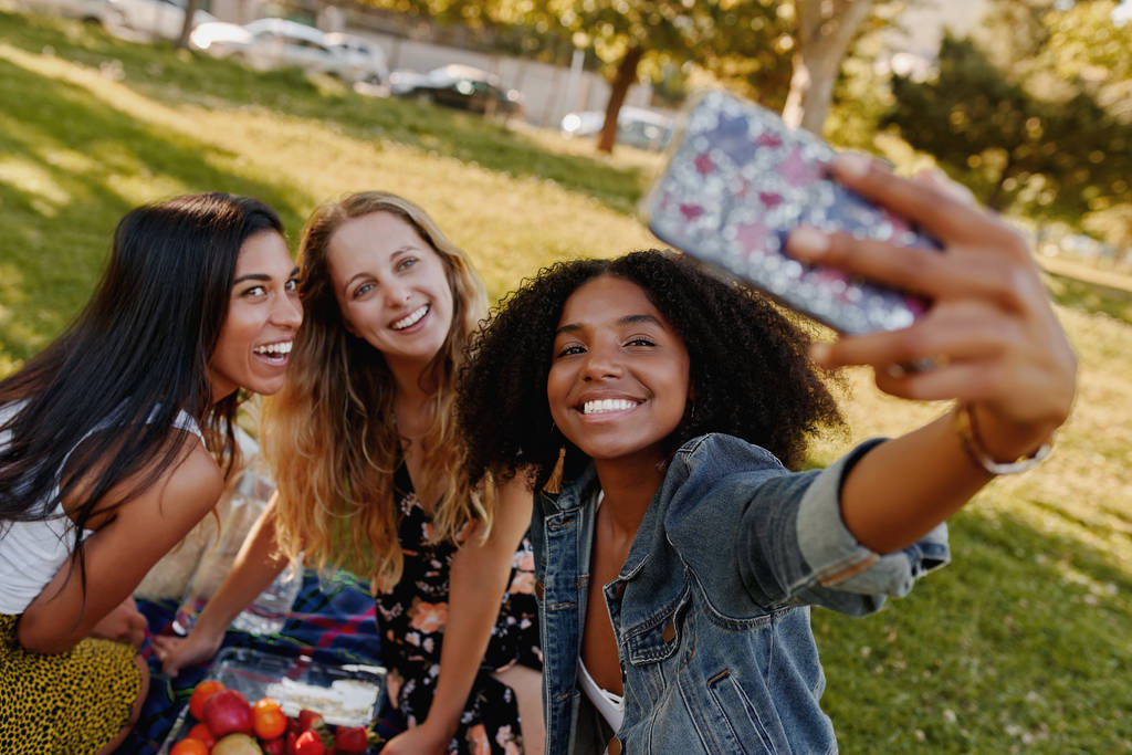Portrét usmívající se mladé africké americké ženy, jak se Selfie se svými kamarádkami na pikniku v parku - Fotografie, Obrázek