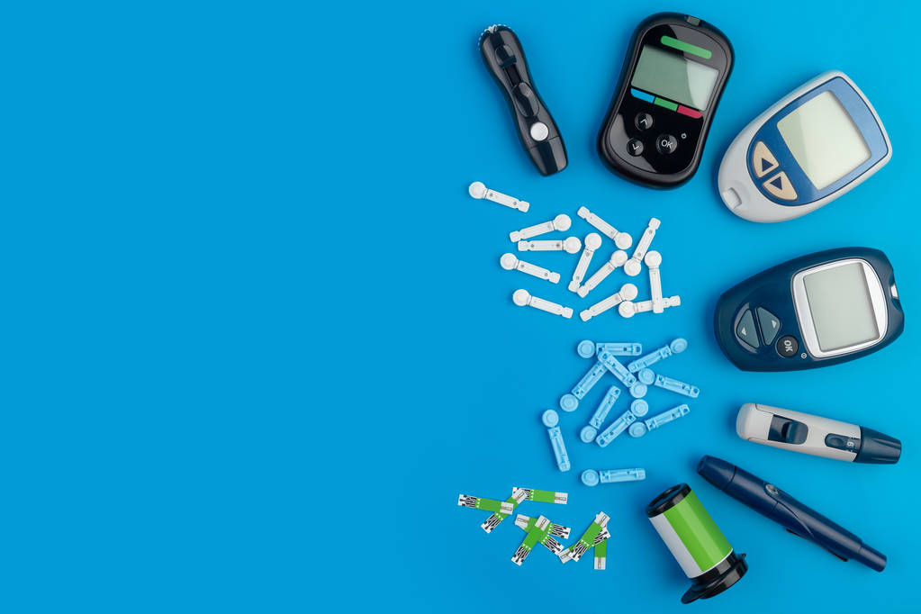 Glukometer. ein Gerät zur Messung des Blutzuckerspiegels. Teststreifen, Pillen auf blauem Hintergrund. - Foto, Bild
