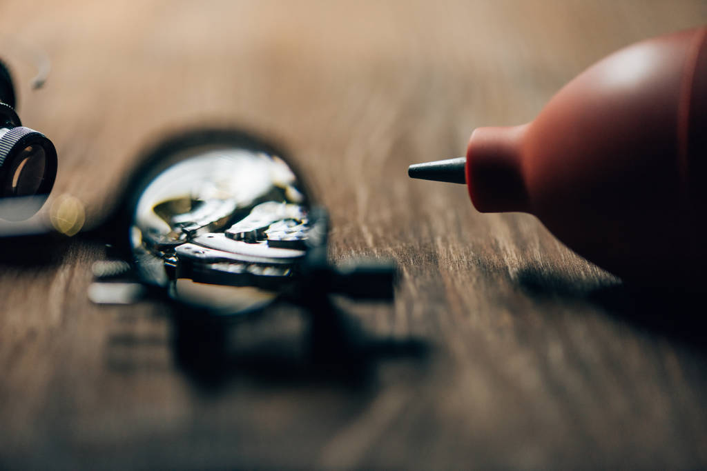 Selective focus of wristwatch, magnifying glass and blower on wooden table - Photo, Image