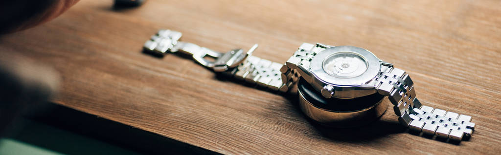 木製のテーブルの上に立つ腕時計のパノラマショット  - 写真・画像