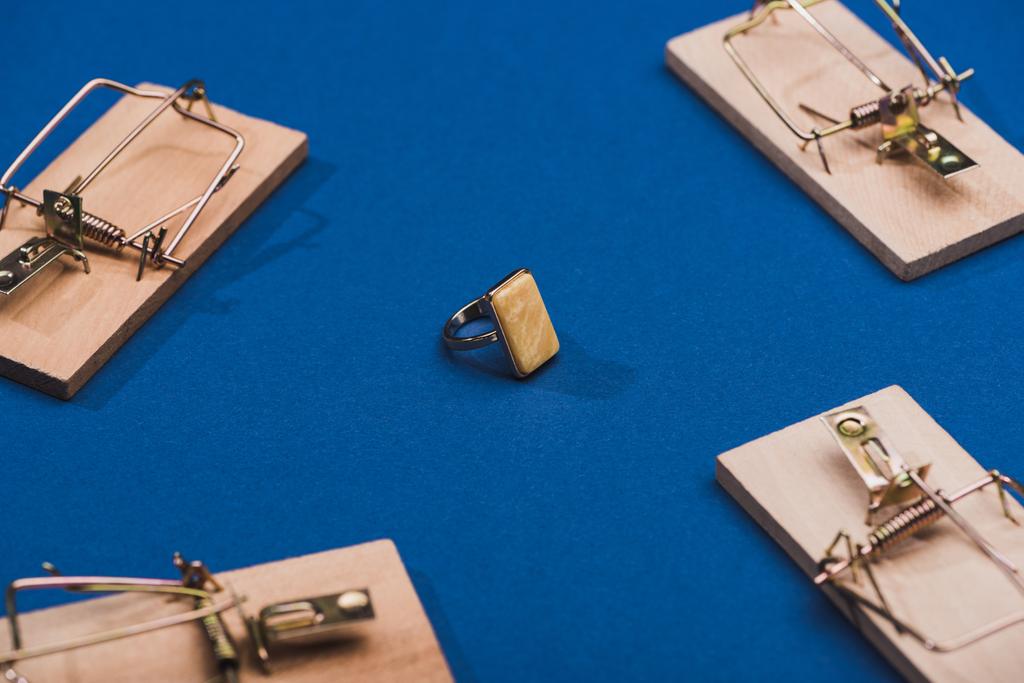 Selectieve focus van sieraden ring met houten muisvallen op blauwe achtergrond - Foto, afbeelding