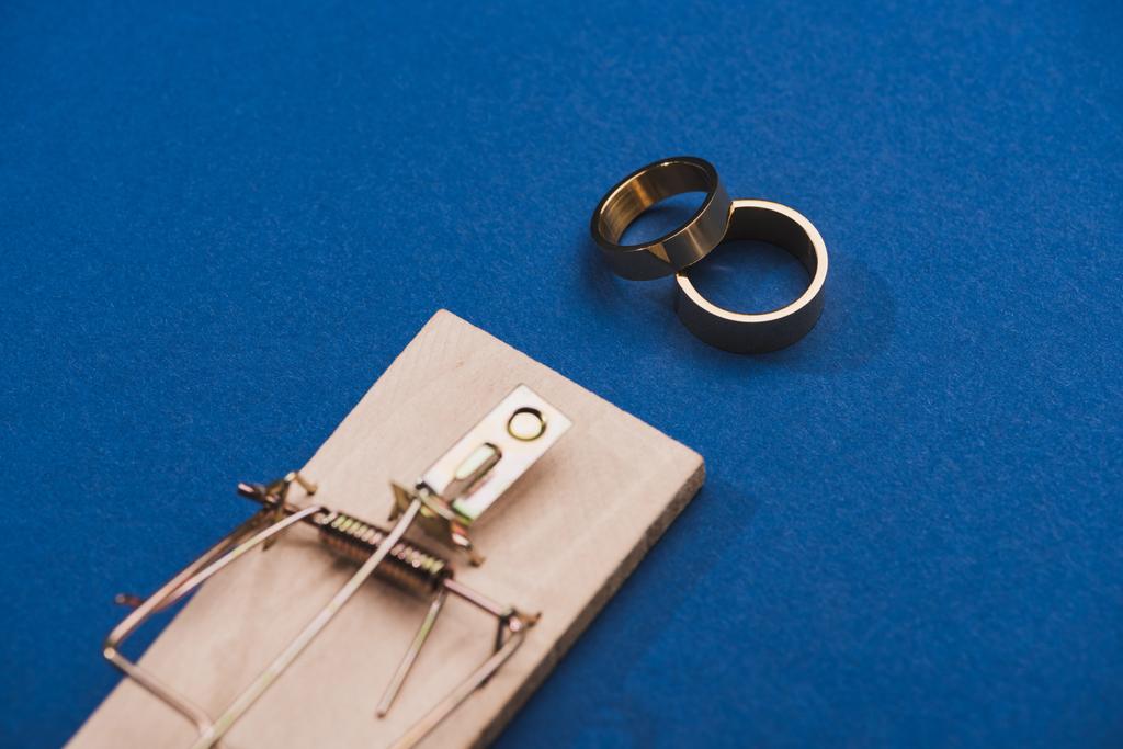 Mavi arka planda fare kapanı olan iki altın yüzüğün seçici odağı - Fotoğraf, Görsel
