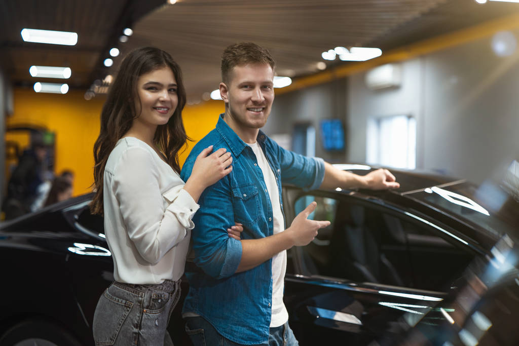 молодая счастливая пара красивый мужчина и красивая женщина ищет новый автомобиль в электромобиле дилерский центр
 - Фото, изображение