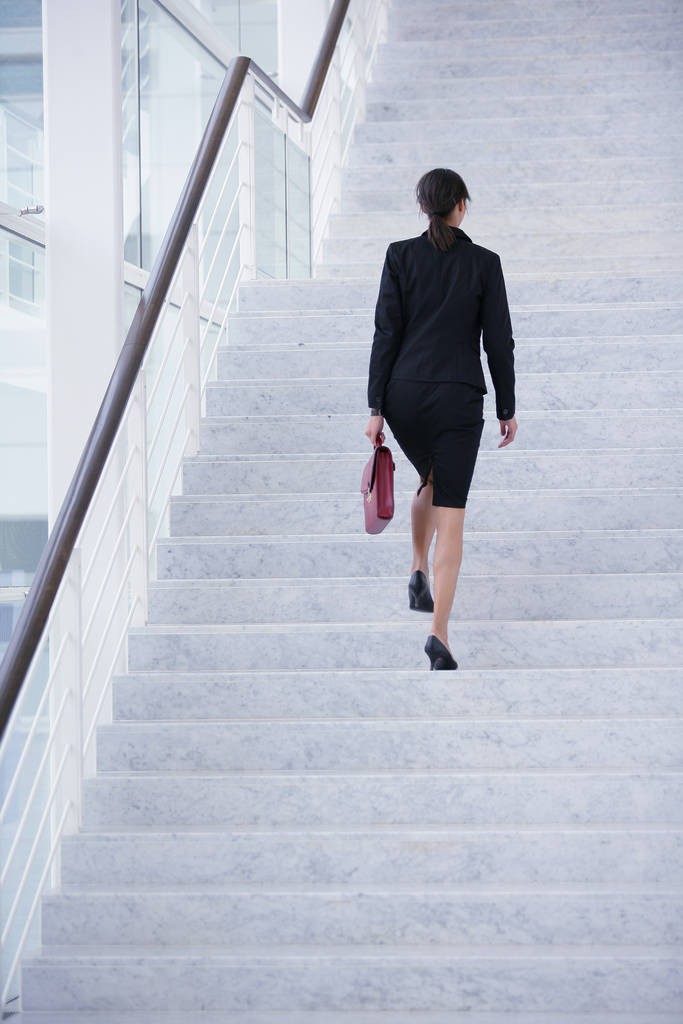 Donna in abito da lavoro salendo le scale di una società moderna - Foto, immagini
