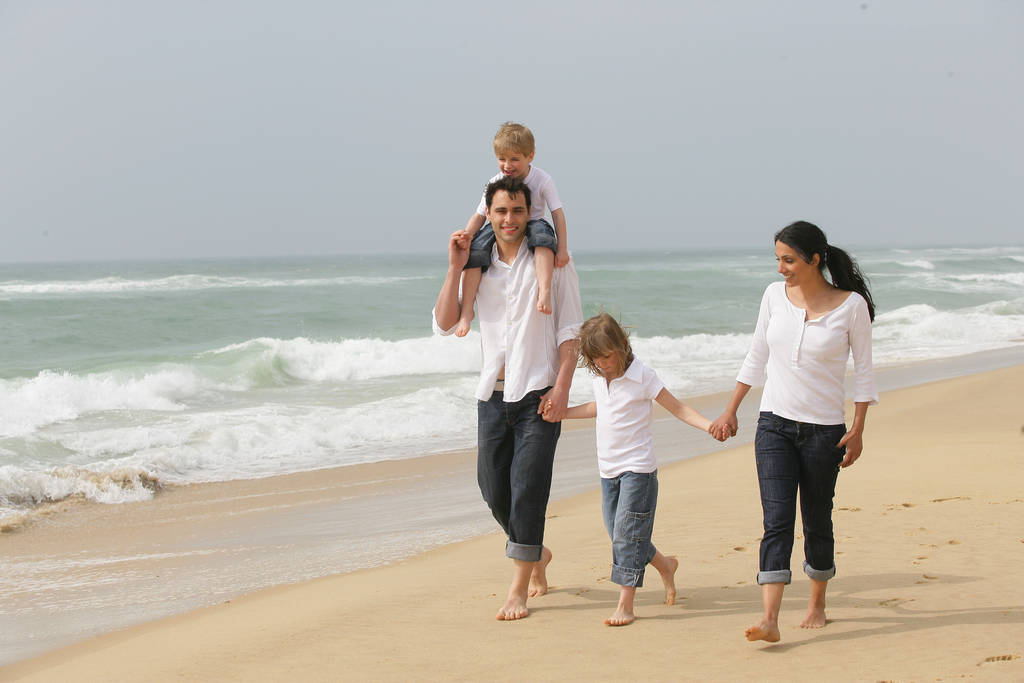 Mann und Frau mit Kindern spazieren am Strand - Foto, Bild