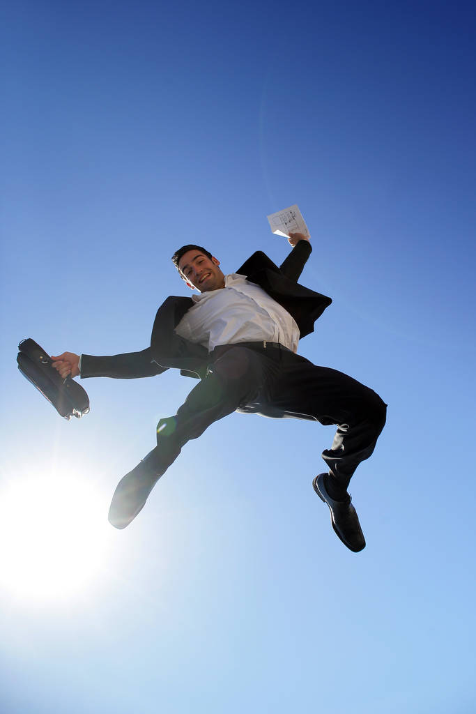 Uśmiechnięty mężczyzna w garniturze z aktówką skaczący w powietrzu - Zdjęcie, obraz