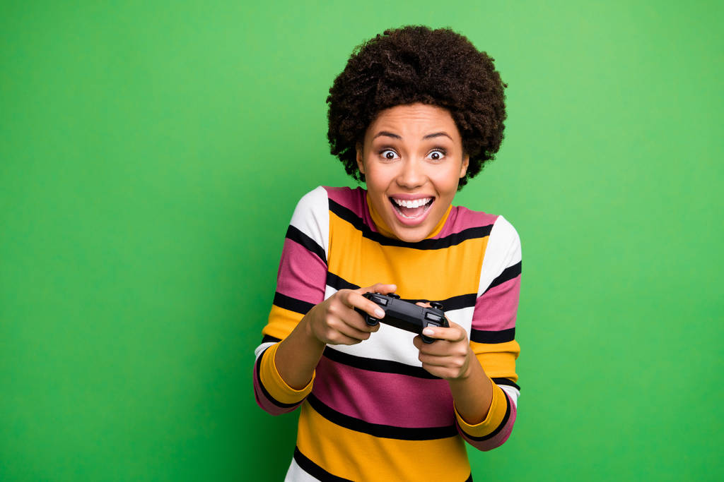 面白い暗い肌の女性の写真良い気分のビデオゲーム中毒ゲーマー興奮ホールドジョイスティックの手を着用カジュアルストライプセーター隔離された緑の色の背景 - 写真・画像