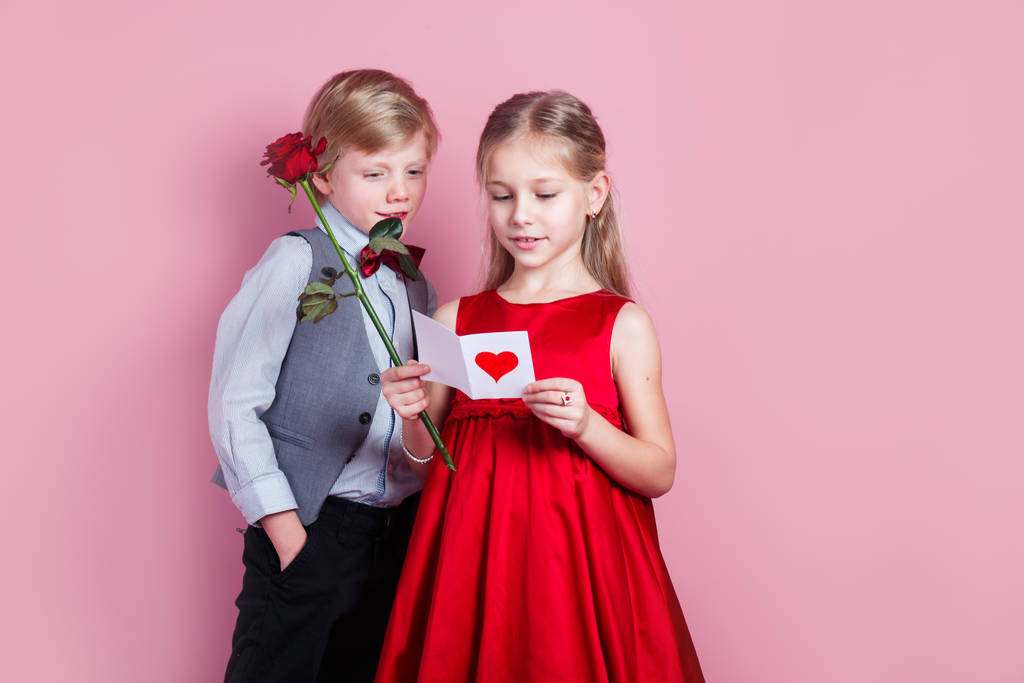 studio portret van een schattig jongetje en meisje met een Valentijnskaart in haar handen - Foto, afbeelding