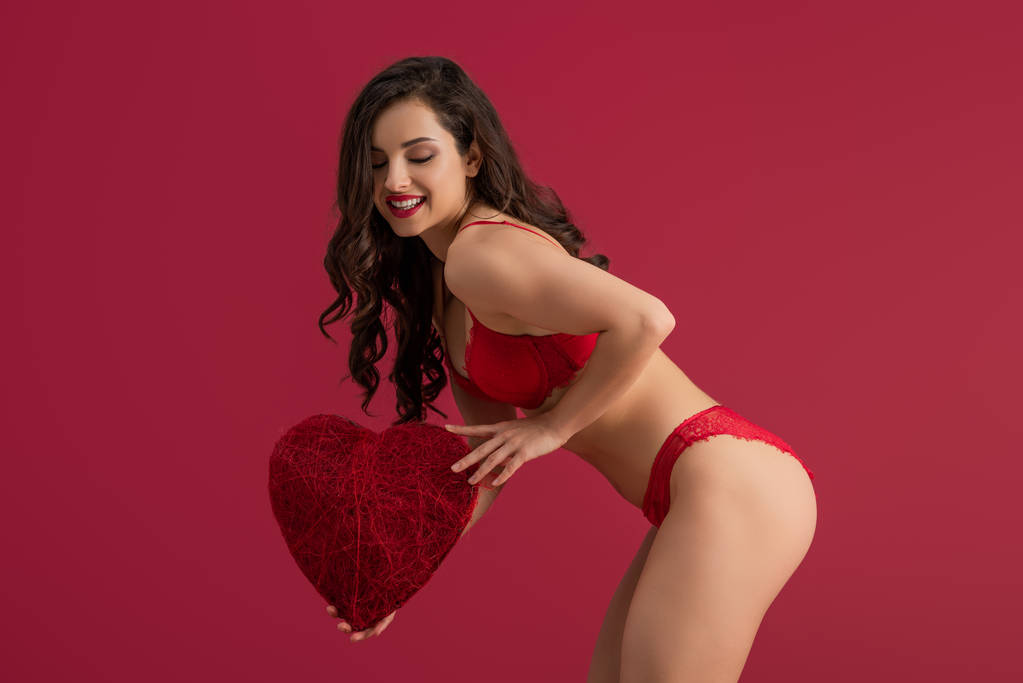 sensual, chica sonriente en lencería sosteniendo corazón decorativo aislado en rojo
 - Foto, Imagen
