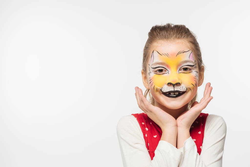 cute kid with tiger muzzle painting on face holding hands near face while looking at camera isolated on white - Photo, Image