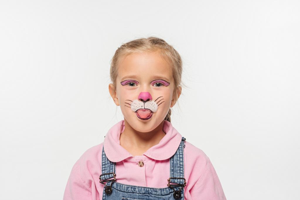 veselé dítě s kočičí náhubek malování na tváři vyčnívající jazyk při pohledu na kameru izolované na bílém - Fotografie, Obrázek