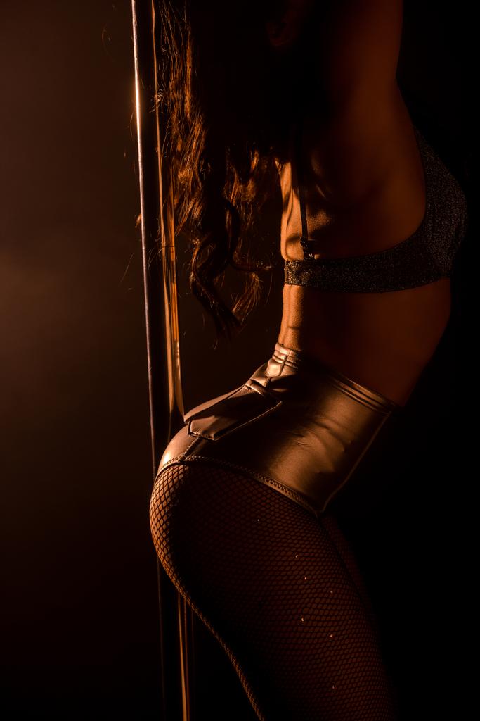 vue recadrée de fille sexy en collants résille et culotte debout près de pylône sur noir
 - Photo, image