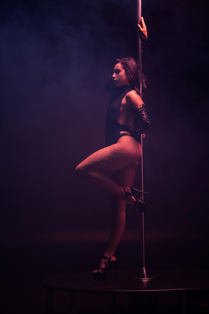 attractive stripper dancing near pylon on blue with smoke  - Photo, Image