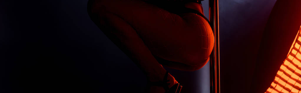 tiro panorámico de sexy stripper pole bailando en negro con iluminación roja
  - Foto, Imagen