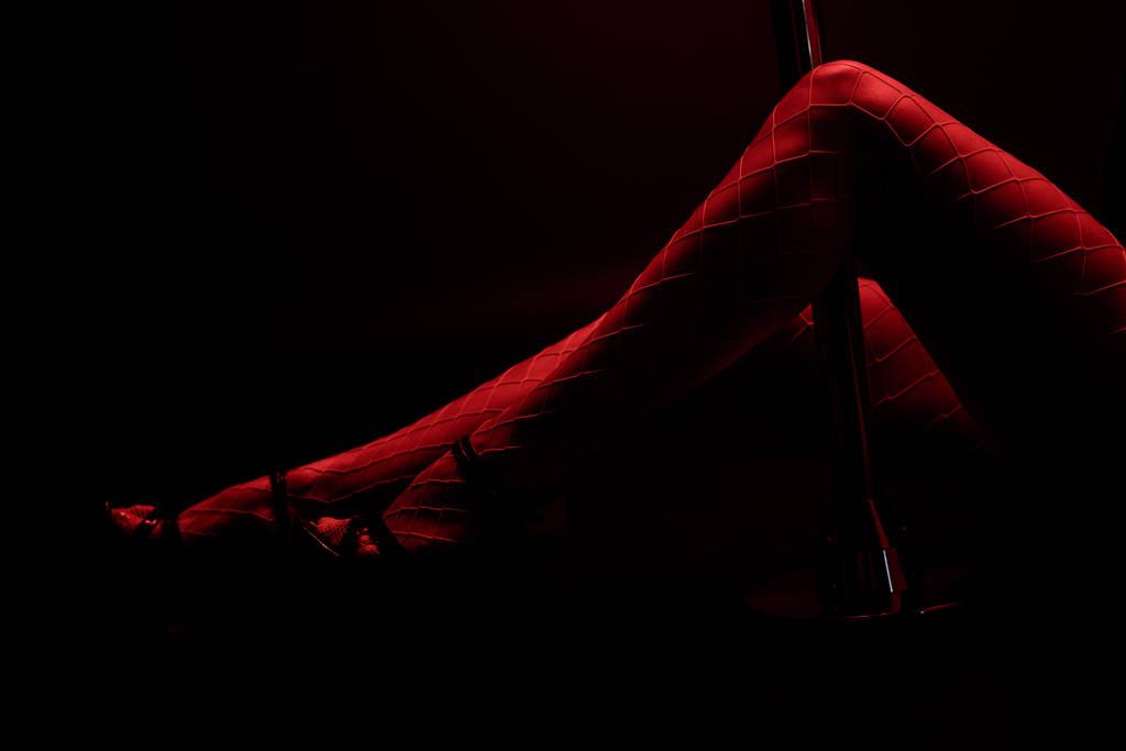 обрізаний вид червоного освітлення на сексуальній смузі ізольовані на чорному з червоним освітленням
  - Фото, зображення