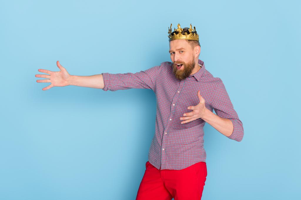 homme choqué avec couronne pointant avec la main sur fond bleu
  - Photo, image