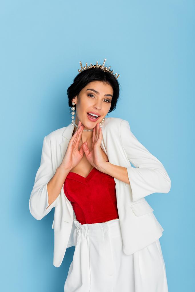 shocked woman with crown looking at camera on blue background  - Photo, Image