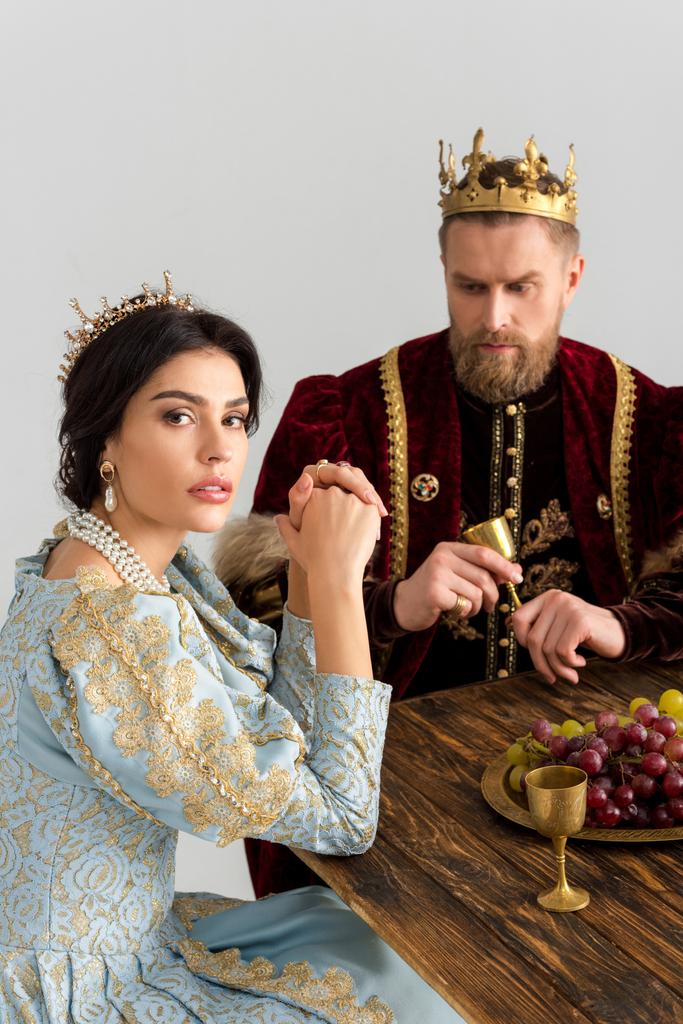 vakava kuningatar ja kuningas kruunut istuu pöydässä eristetty harmaa
 - Valokuva, kuva