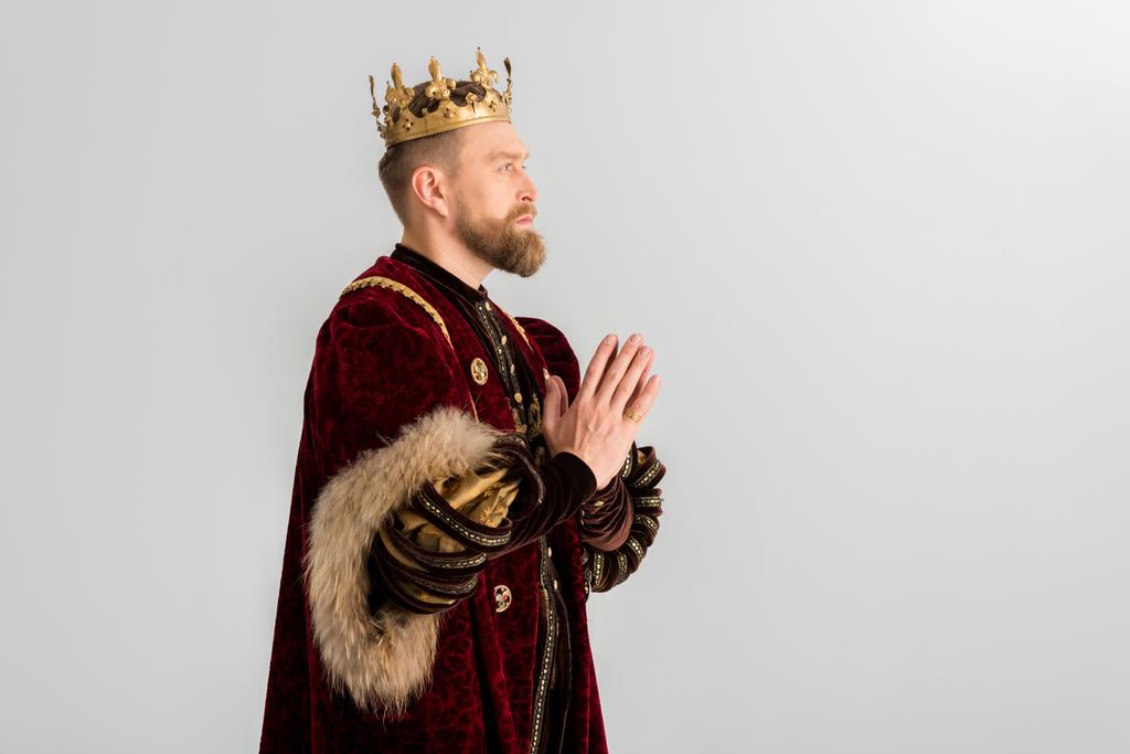 widok z boku króla z koroną modląc się odizolowany na szarości - Zdjęcie, obraz