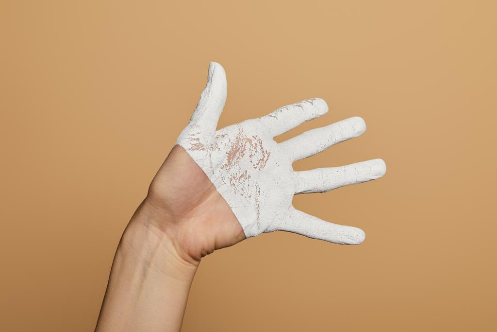 καλλιεργημένη άποψη της γυναίκας με λευκό ζωγραφισμένο χέρι που δείχνει παλάμη απομονωμένη σε μπεζ - Φωτογραφία, εικόνα