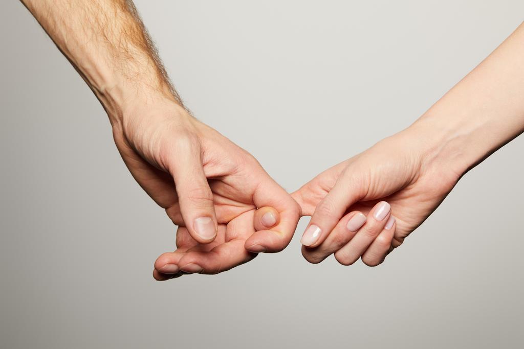καλλιεργημένη άποψη του άνδρα και της γυναίκας που κρατούν τα δάχτυλα απομονωμένα σε λευκό - Φωτογραφία, εικόνα