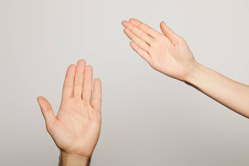 Ausgeschnittene Ansicht von Mann und Frau mit vereinzelten Handflächen auf grau - Foto, Bild
