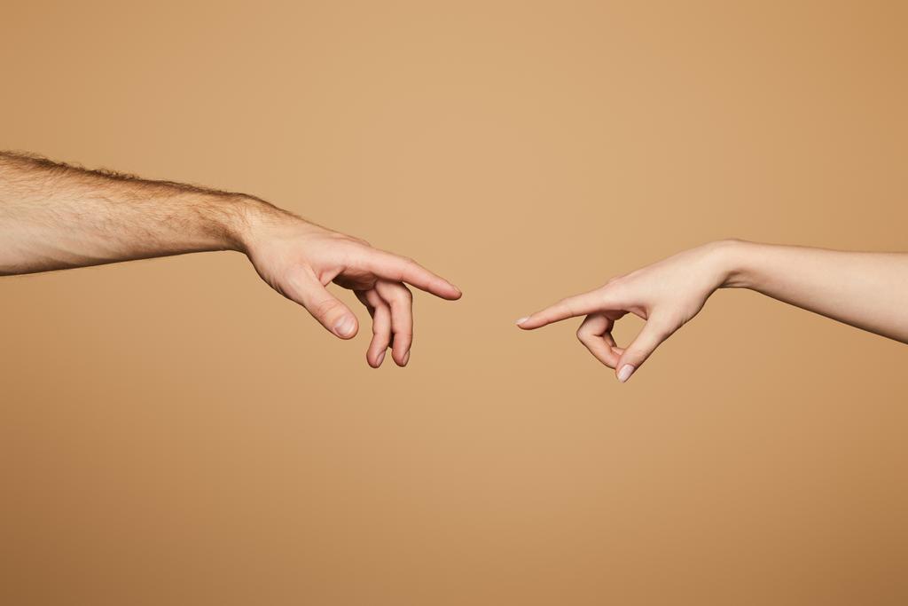 καλλιεργημένη άποψη του άνδρα και της γυναίκας που φθάνουν το ένα το άλλο με τα δάχτυλα απομονωμένα σε μπεζ - Φωτογραφία, εικόνα