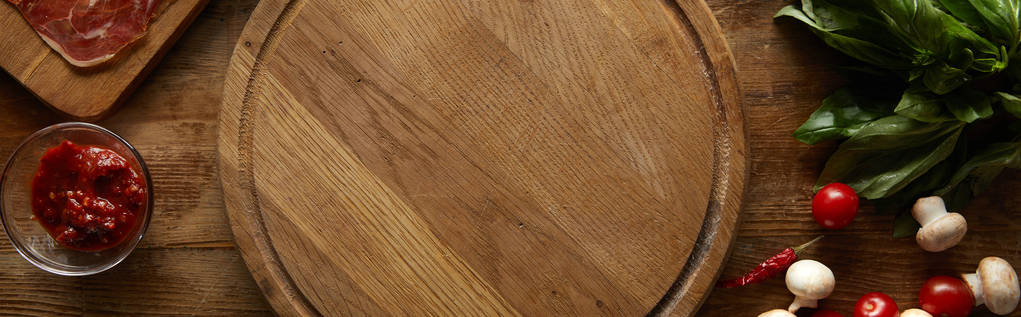 Vista superior de tabla de cortar con ingredientes para pizza sobre fondo de madera, plano panorámico
 - Foto, Imagen