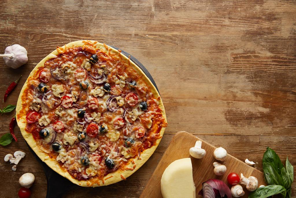 Вид зверху на піцу та овочі на дерев'яному фоні
 - Фото, зображення