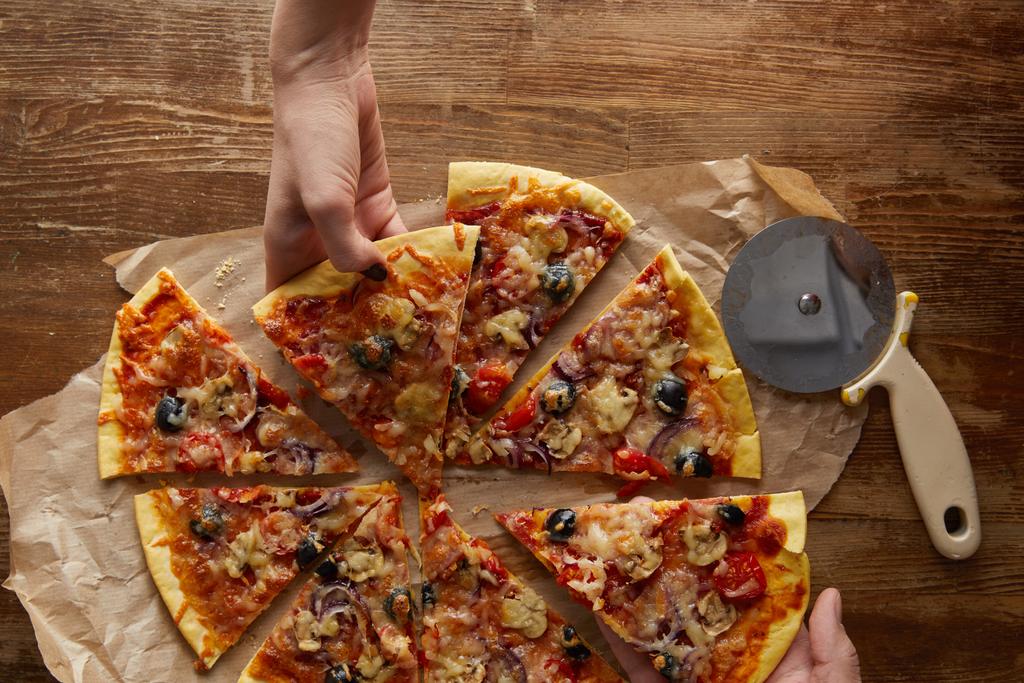 Vista recortada de la pareja comiendo pizza sobre fondo de madera
 - Foto, imagen
