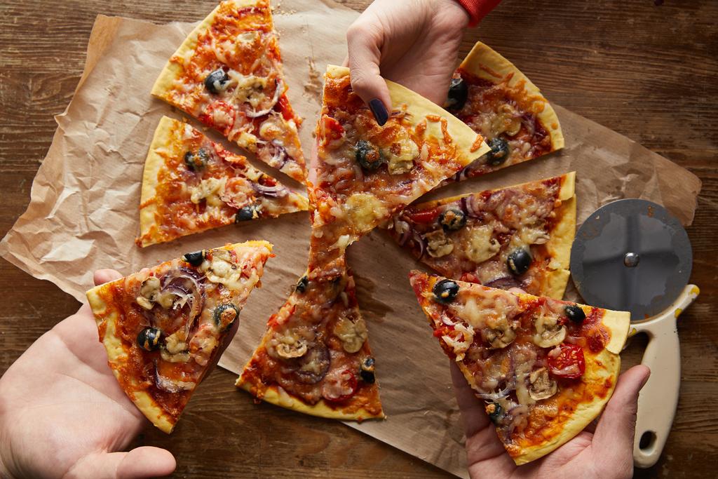 Προβολή των φίλων που τρώνε πίτσα σε ξύλινο φόντο - Φωτογραφία, εικόνα