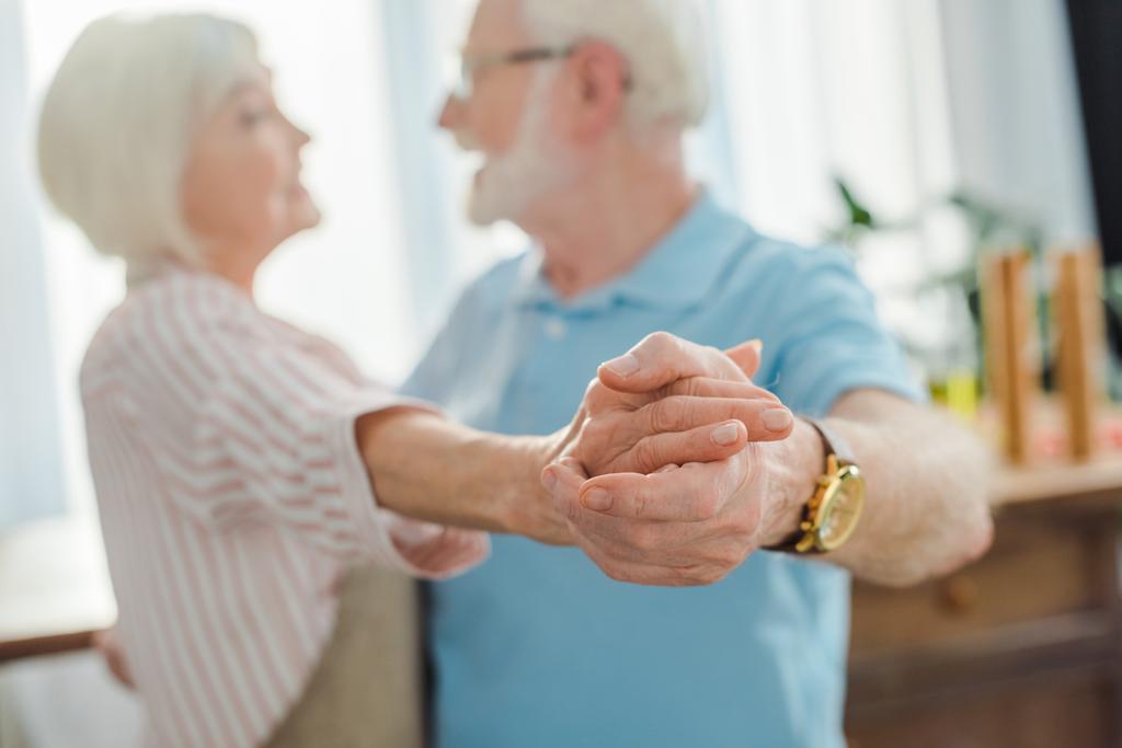 Válogatott fókusz idős pár kéz a kézben, miközben táncol a konyhában - Fotó, kép