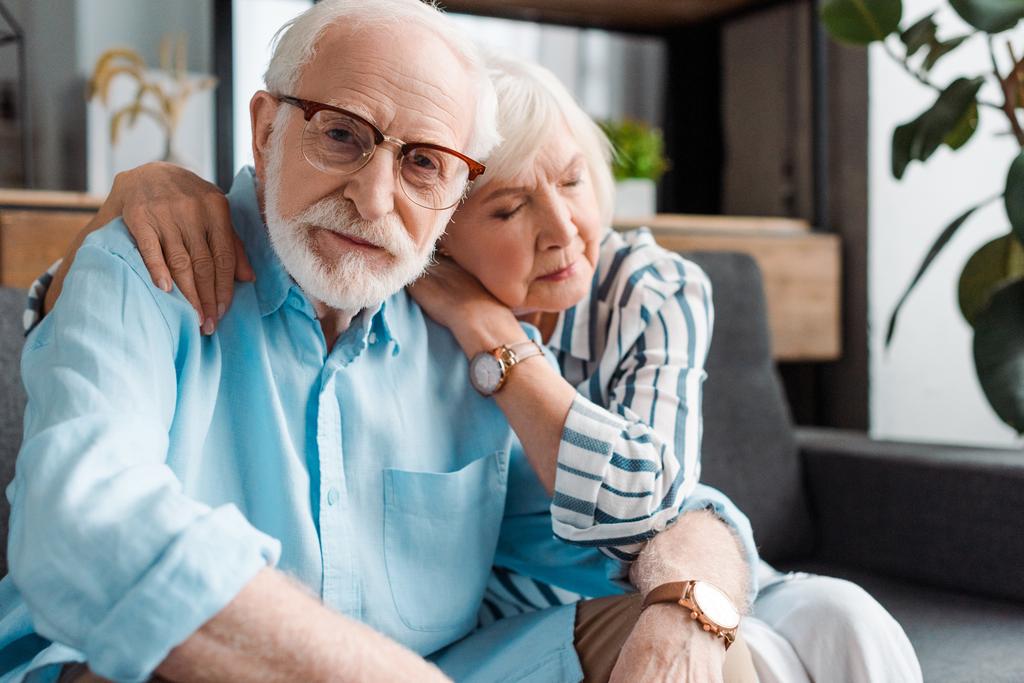 Вибірковий фокус старшого чоловіка, дивлячись на камеру дружиною на дивані
 - Фото, зображення