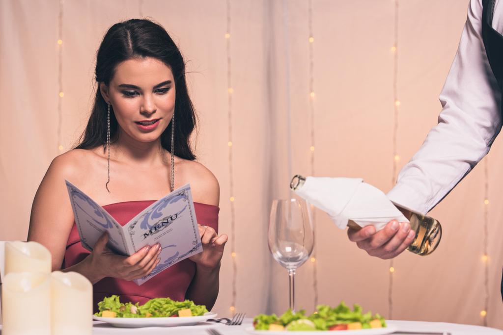 attraente, elegante ragazza menu di lettura mentre cameriere versando vino bianco in vetro
 - Foto, immagini