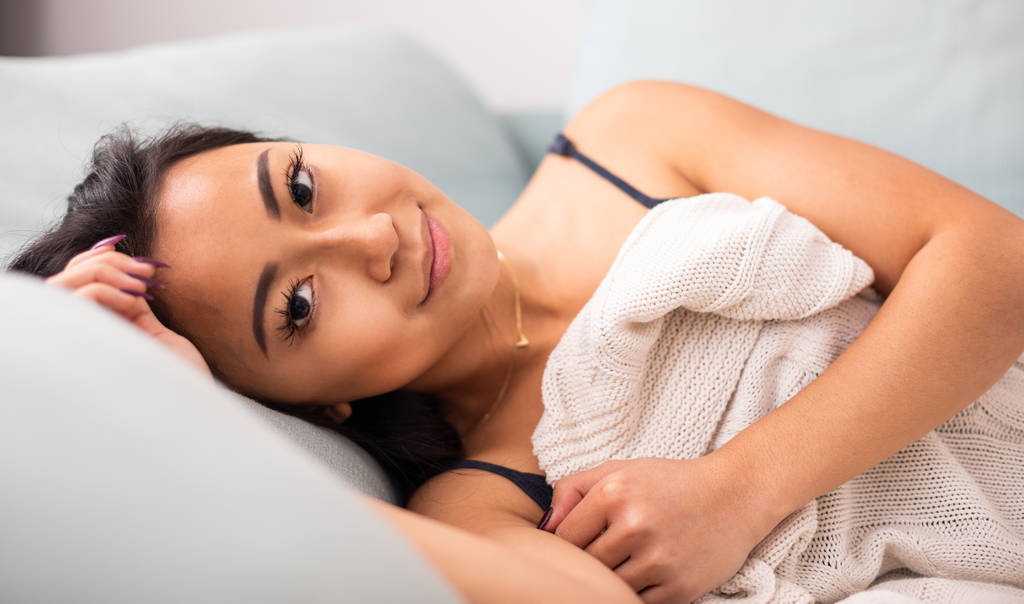 Rahatlamış Asyalı genç kadın evde yatakta yatıyor. - Fotoğraf, Görsel