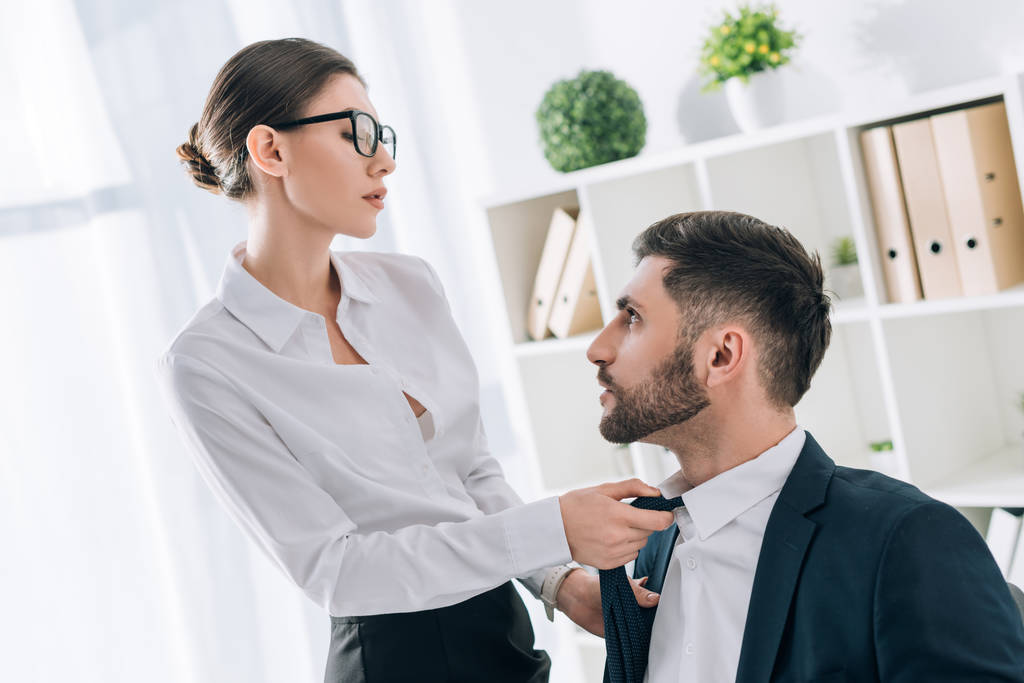 attractive secretary pulling tie of handsome businessman in office  - Photo, Image