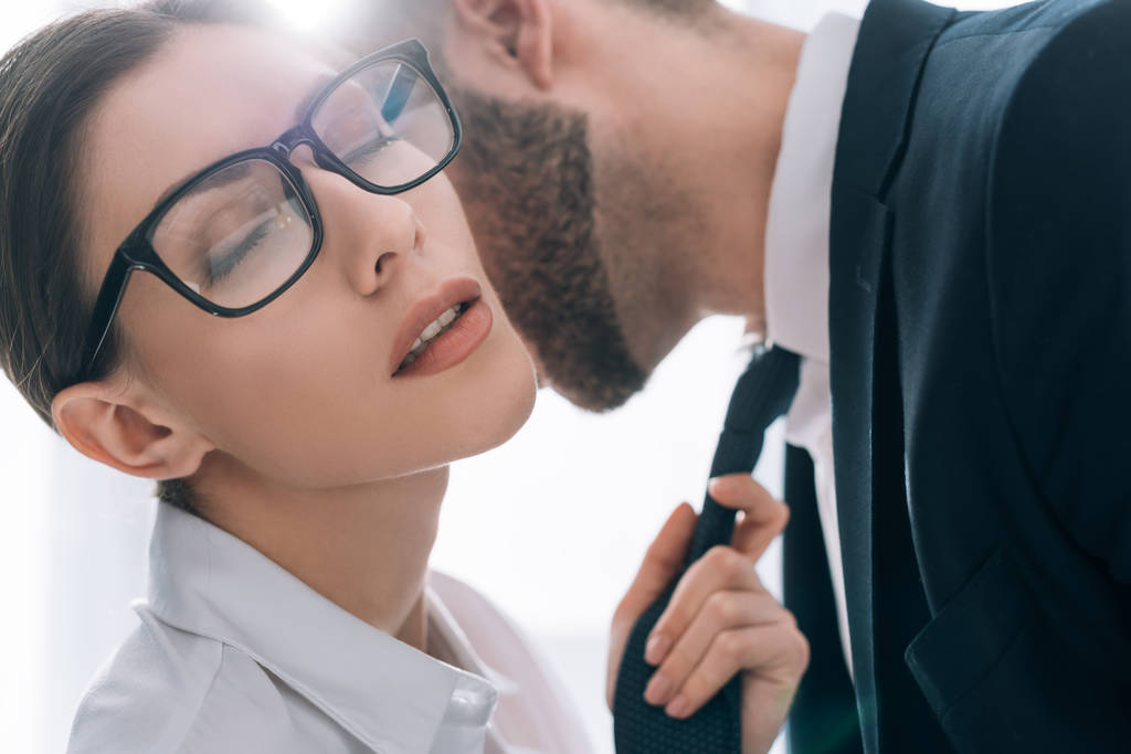uomo d'affari baciare attraente segretaria con gli occhi chiusi in ufficio
  - Foto, immagini